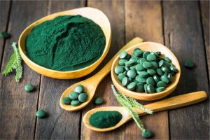 Spiruline en poudre et en comprimés dans des cuillères en bois